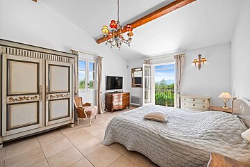 A bedroom with a large bed a dresser and a television