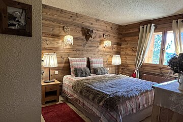 A bedroom with a wooden wall and a bed