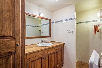 A bathroom with white tiles and a wooden sink