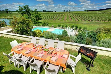 A table with plates and utensils on it in front of a swimming pool