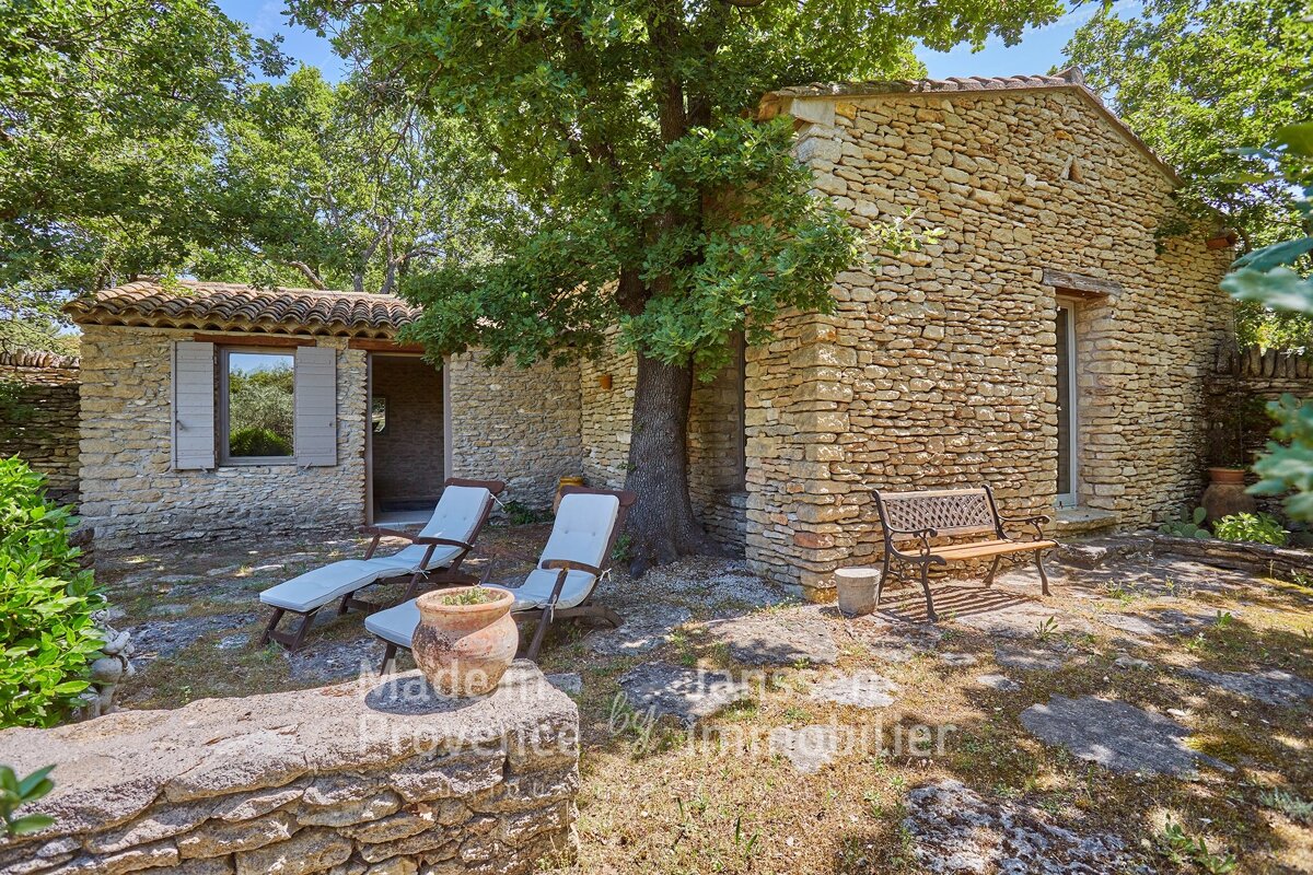 A stone building with a bench and chairs in front of it