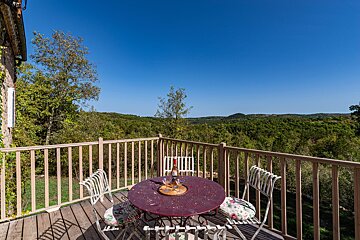 A balcony with a table and chairs and a bottle of wine on it