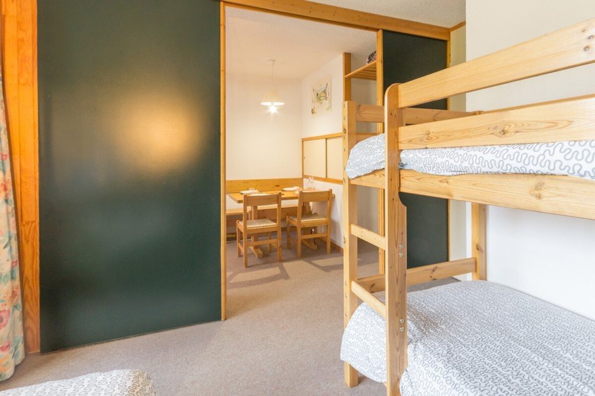 A bunk bed in a room with a table and chairs