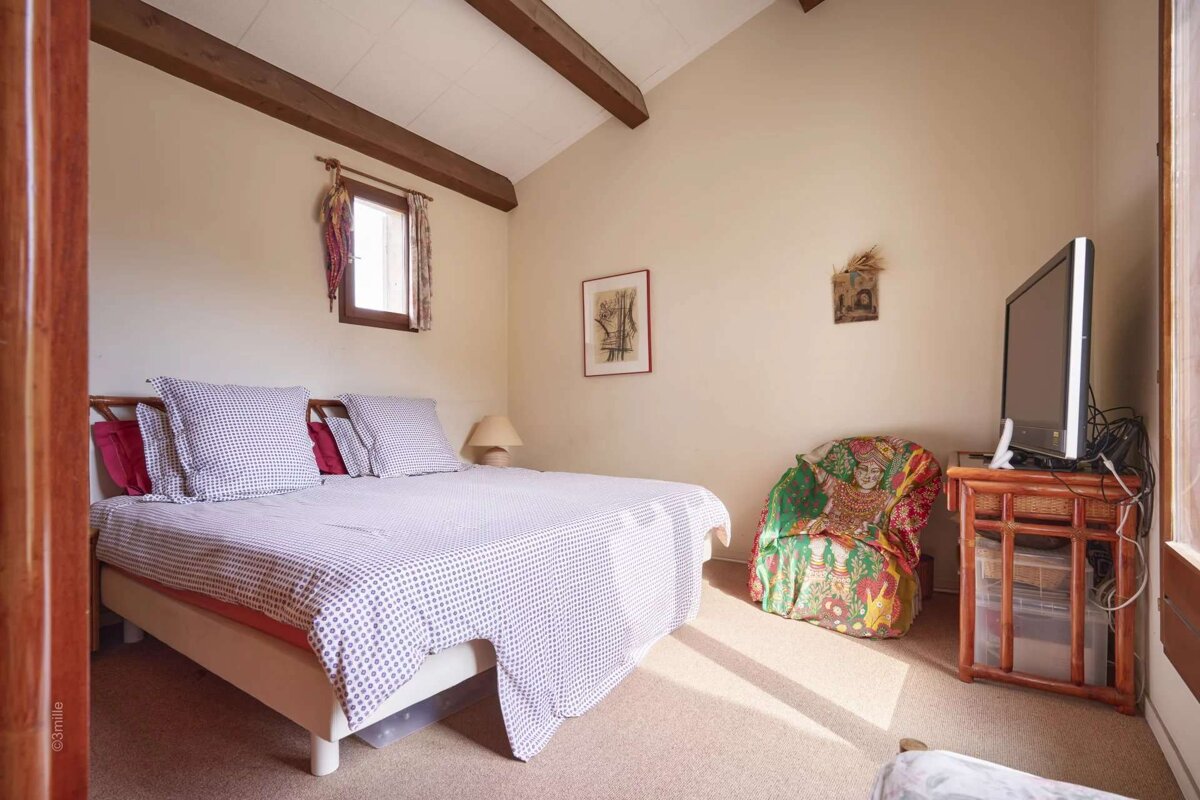 A bedroom with a bed a chair and a television