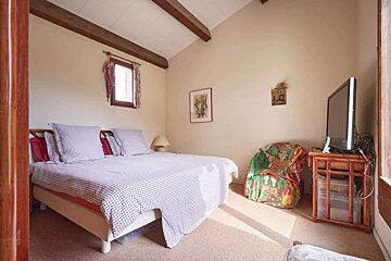 A bedroom with a bed a chair and a television