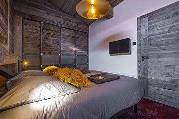 A bedroom with a bed and a television on the wall