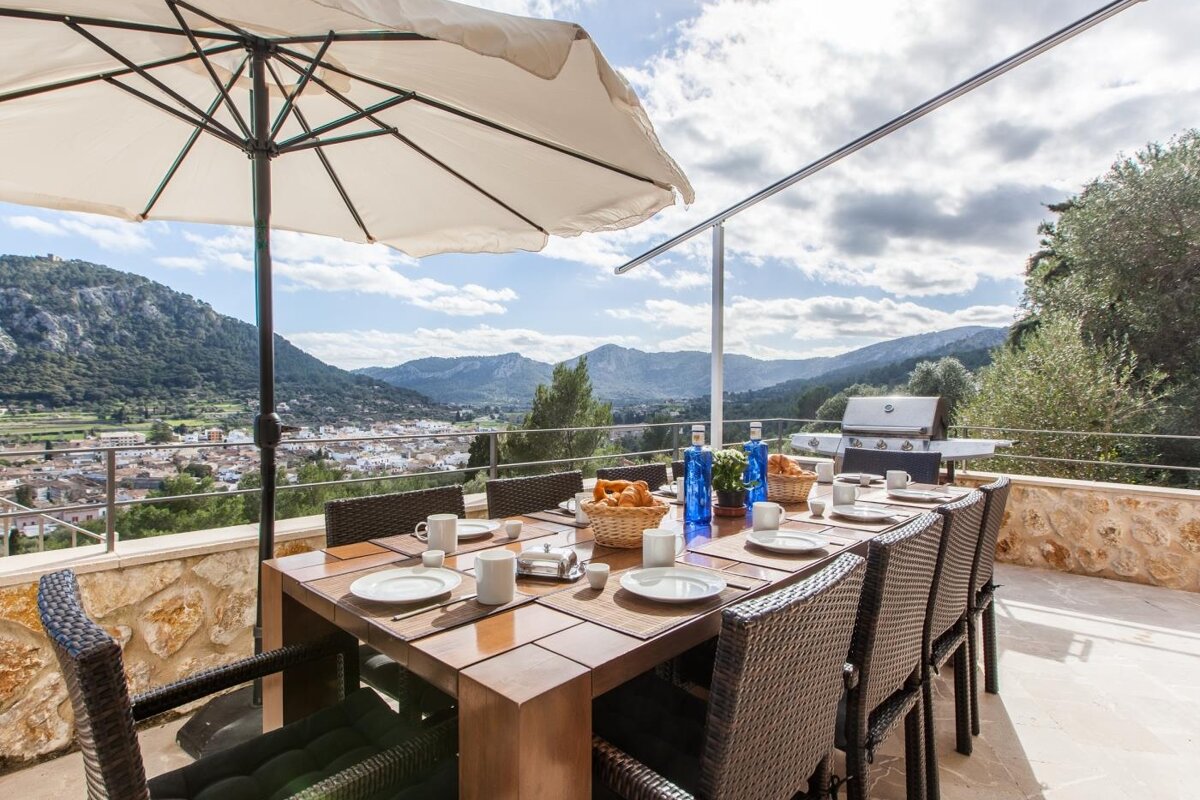 A dining table with a view of mountains and a grill