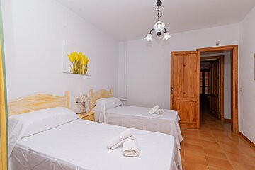 A bedroom with two beds and a picture of yellow flowers on the wall