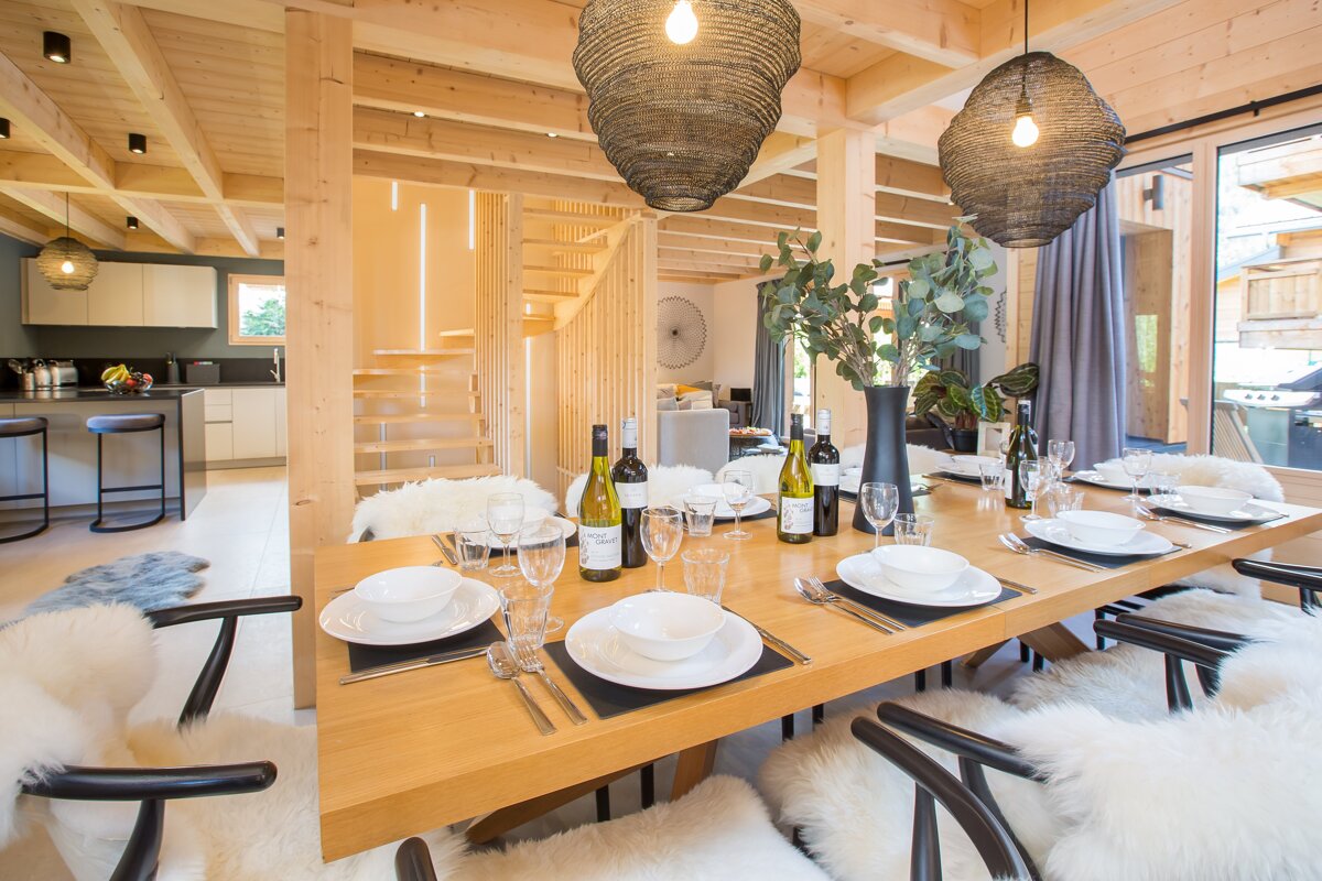 A dining room table with plates and wine bottles on it