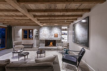 A living room with a stone fireplace and wooden beams