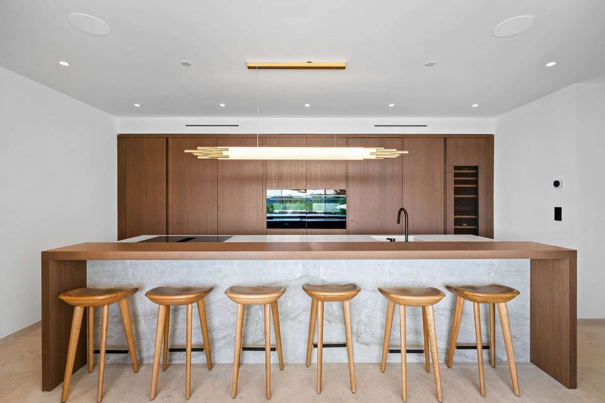 A kitchen with a marble counter top and wooden stools
