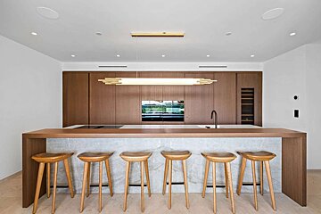 A kitchen with a marble counter top and wooden stools