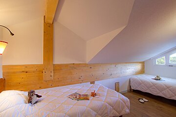 A bedroom with two beds and a teddy bear on the bed