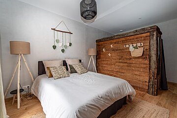A bedroom with a wooden wall and a bed