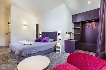 Modern bedroom featuring purple accents, a double bed, built-in shelving, a desk, and a bright pink armchair in the foreground.