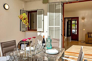 A bottle of wine sits on a table with plates and glasses
