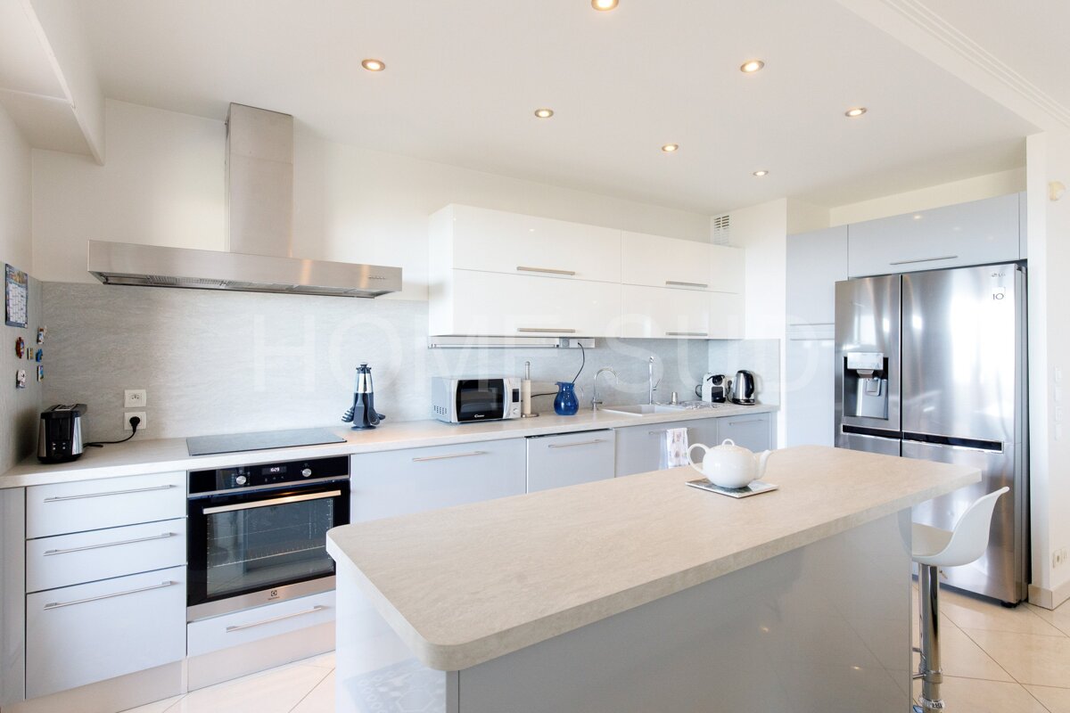 A kitchen with white cabinets and a stainless steel refrigerator