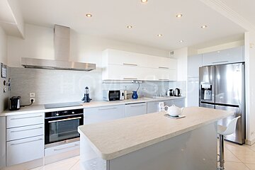 A kitchen with white cabinets and a stainless steel refrigerator