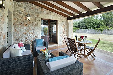 A patio with wicker furniture and a table and chairs