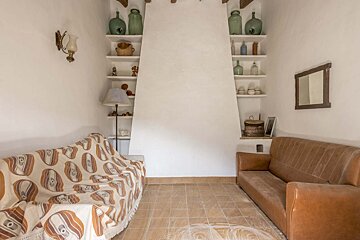 A living room with a couch and shelves with vases on them