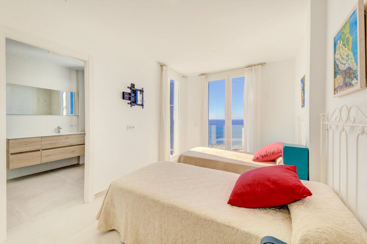 A bedroom with two beds and a television mounted on the wall