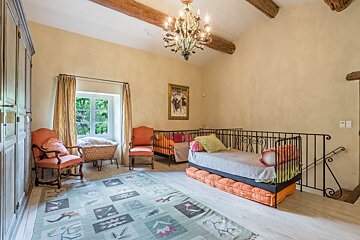 A bedroom with a bed and chairs and a chandelier