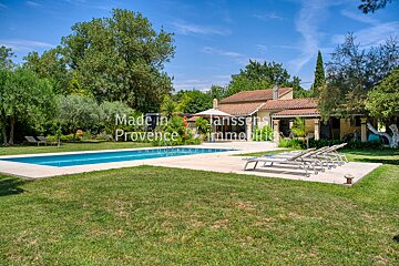 A large swimming pool is surrounded by lawn chairs and a house that says made in provence