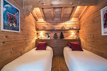 Two twin beds in a wooden room with a poster on the wall that says chaconly