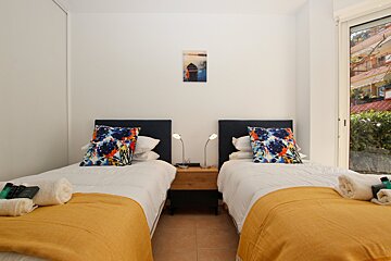 A bedroom with two beds and a painting on the wall