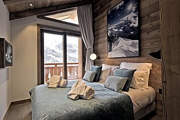 A bedroom with a painting on the wall above the bed