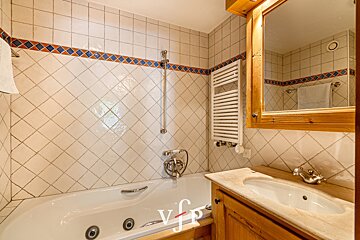 A bathroom with a bathtub and a sink with the letter v on the bottom