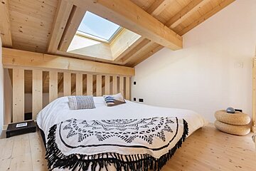 A bedroom with a bed and a skylight above it