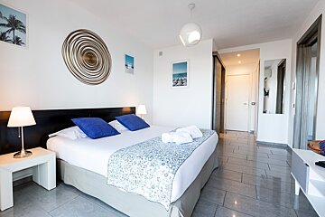 A hotel room with a king size bed and blue pillows