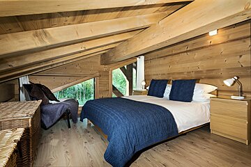 A bedroom with a bed and two nightstands in the attic