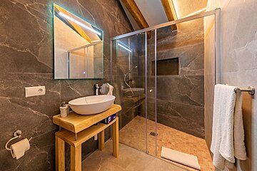 A bathroom with a sink a mirror and a walk in shower