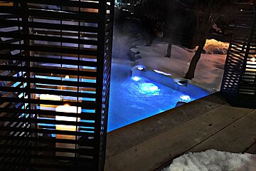 A candle is lit in front of a pool with blue lights