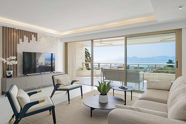 Modern living room with stylish furniture, a TV, and a balcony offering stunning sea and mountain views.