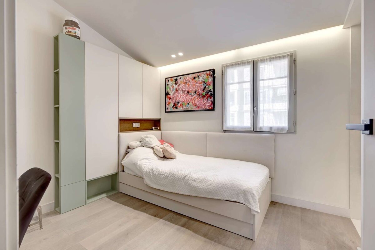 A bright, modern bedroom featuring a white bed with built-in storage, 