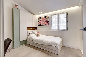 A bright, modern bedroom featuring a white bed with built-in storage, 