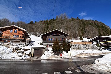 A large wooden and stone building with mountains in the background