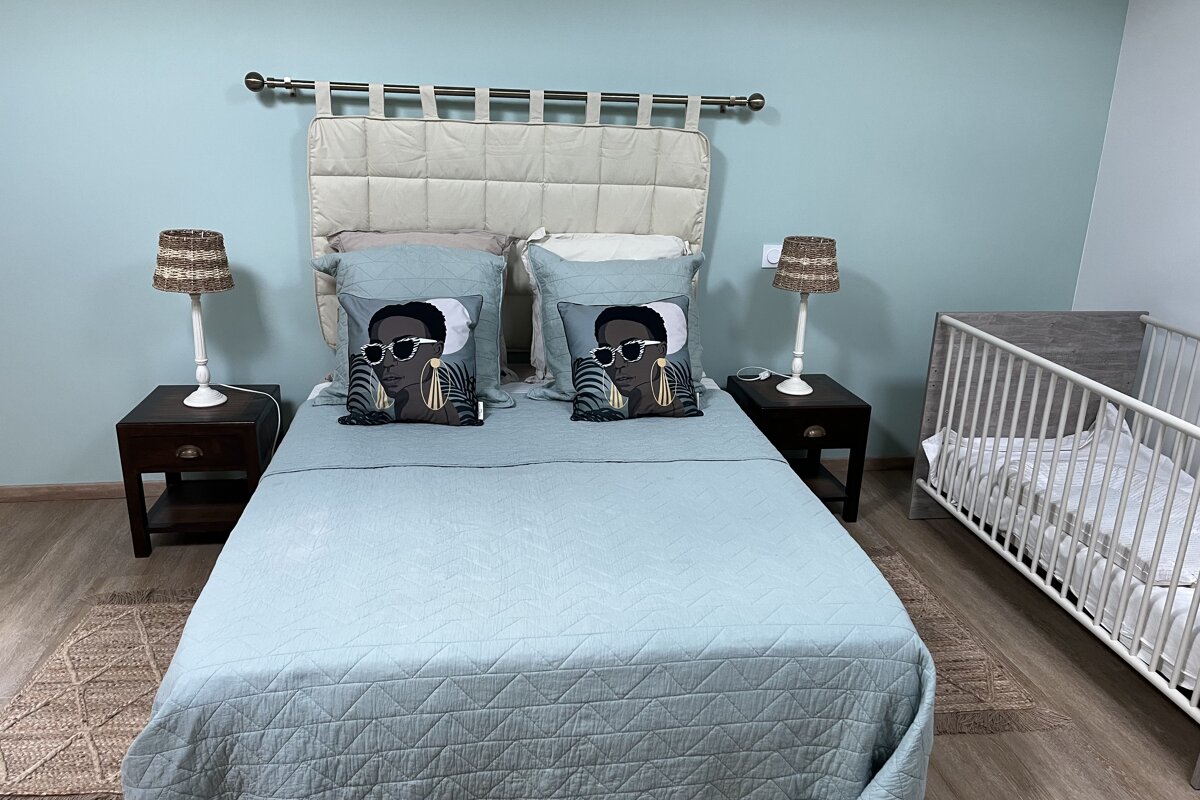 A bedroom with a bed a crib and two lamps