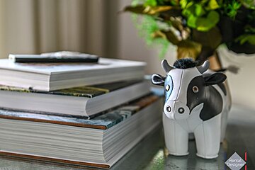 A black and white cow figurine sits on top of a stack of books
