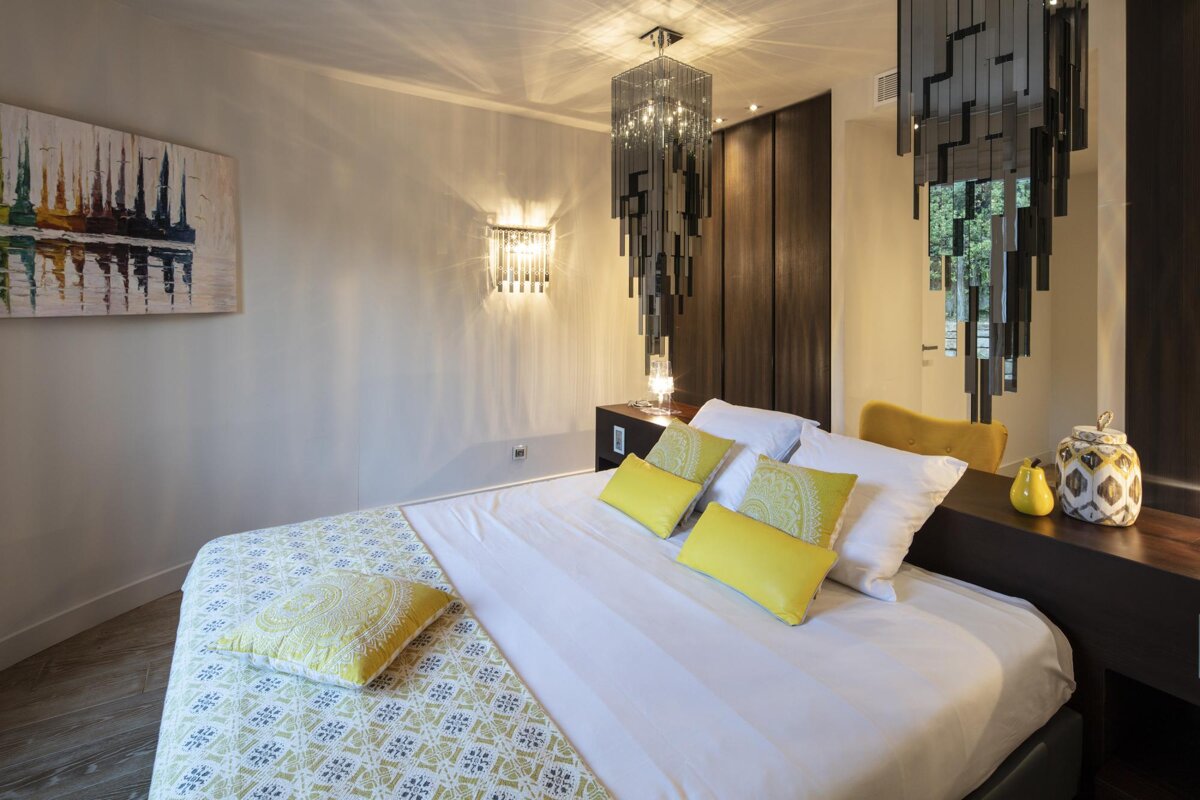 A bedroom with a painting on the wall above the bed