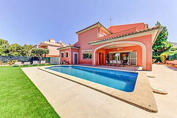 A large pink house with a large swimming pool in front of it