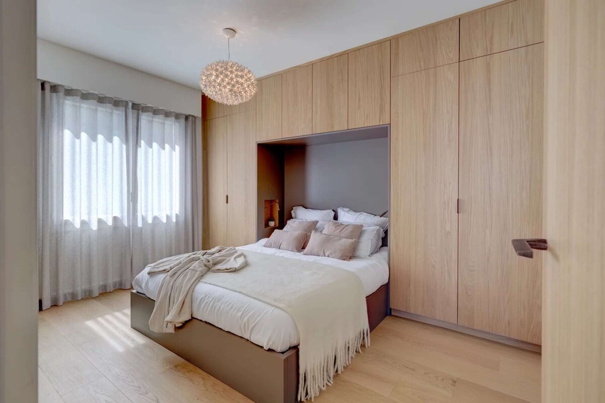A bedroom with a bed surrounded by wooden cabinets