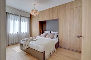 A bedroom with a bed surrounded by wooden cabinets