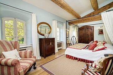 A bedroom with a canopy bed and a chair with the letter a on it