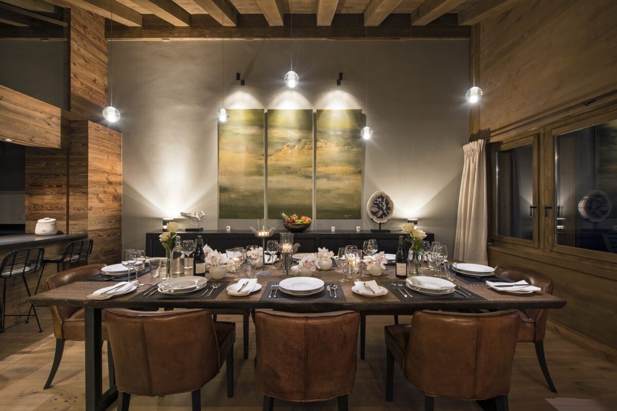 A dining room with a table and chairs and a painting on the wall