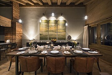 A dining room with a table and chairs and a painting on the wall