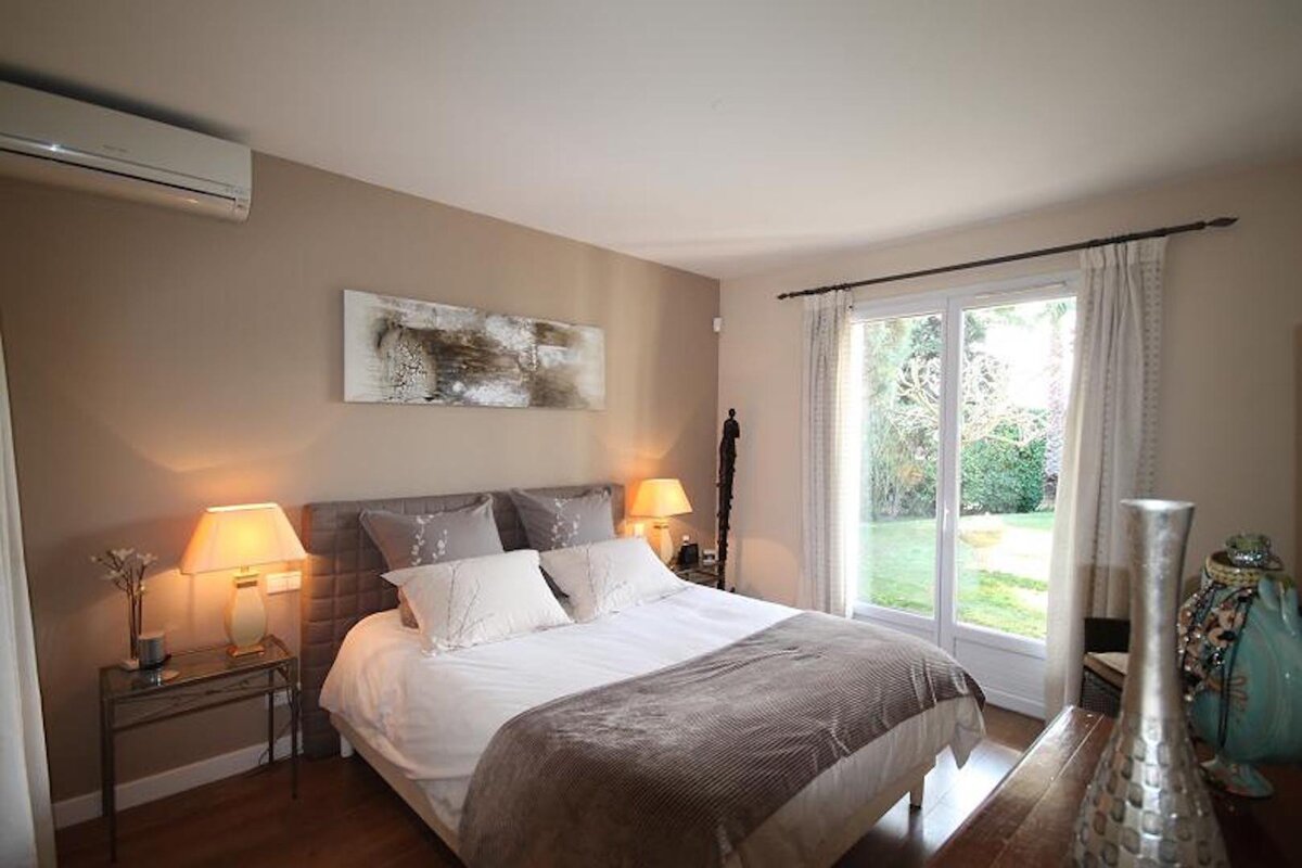 A bedroom with a painting on the wall above the bed